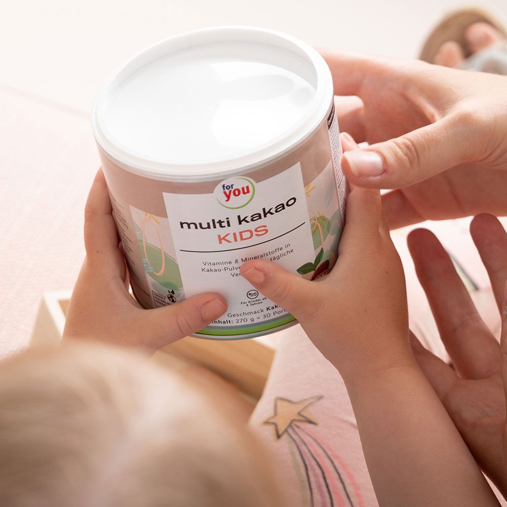 Dose mit Aufschrift "for you multi kakao KIDS". Hände halten die Dose. Aufdruck: Vitamine & Mineralstoffe in Kakao-Pulver.