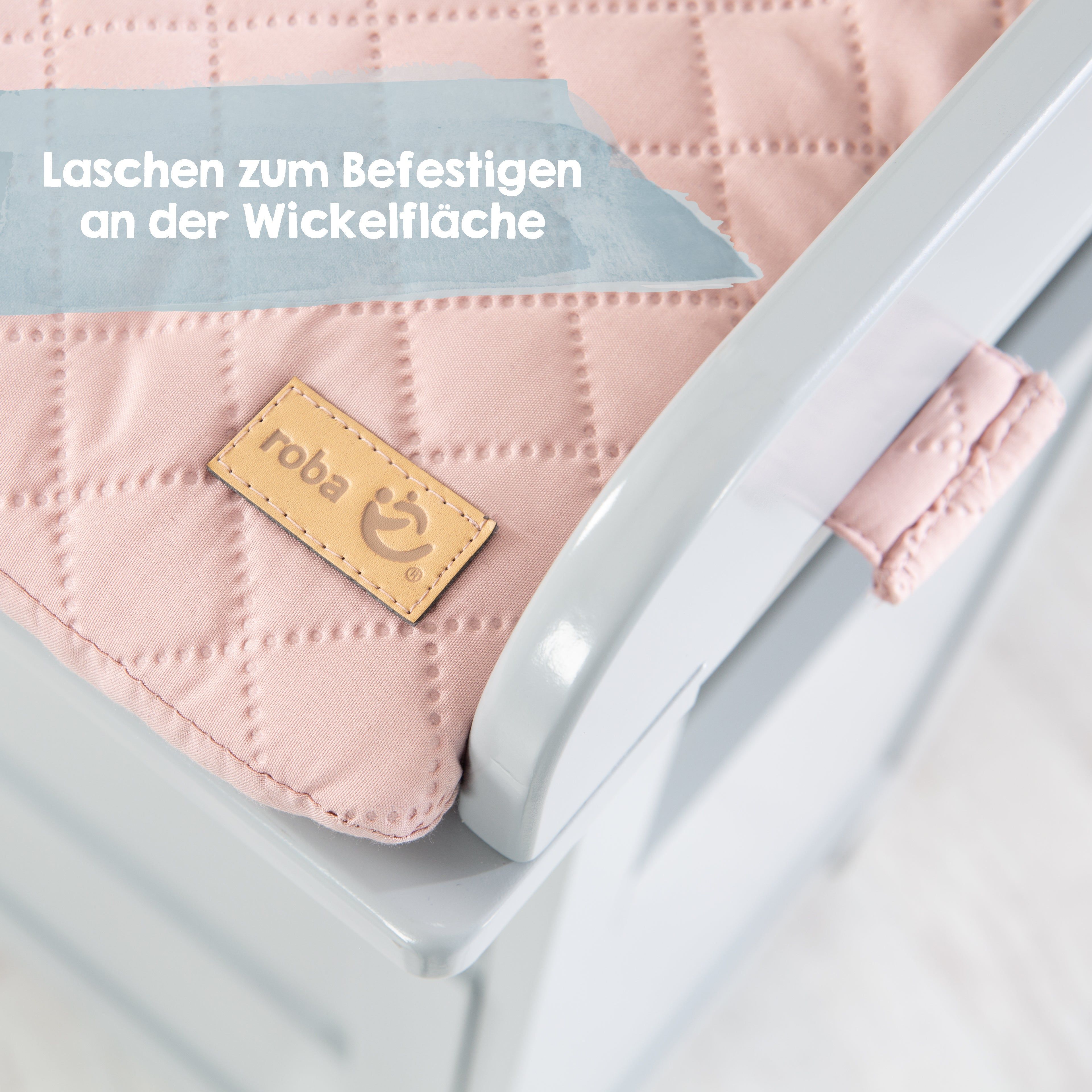 Detailansicht der Wickelauflage. Rosa Steppung, braunes Label mit "roba" Logo. Laschen zur Befestigung.