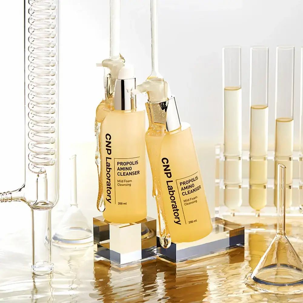 Zwei gelbe Flaschen mit Pumpe. Aufschrift: CNP Laboratory, Propolis Amino Cleanser, Mild Foam Cleansing. 200 ml. Labor-Hintergrund.