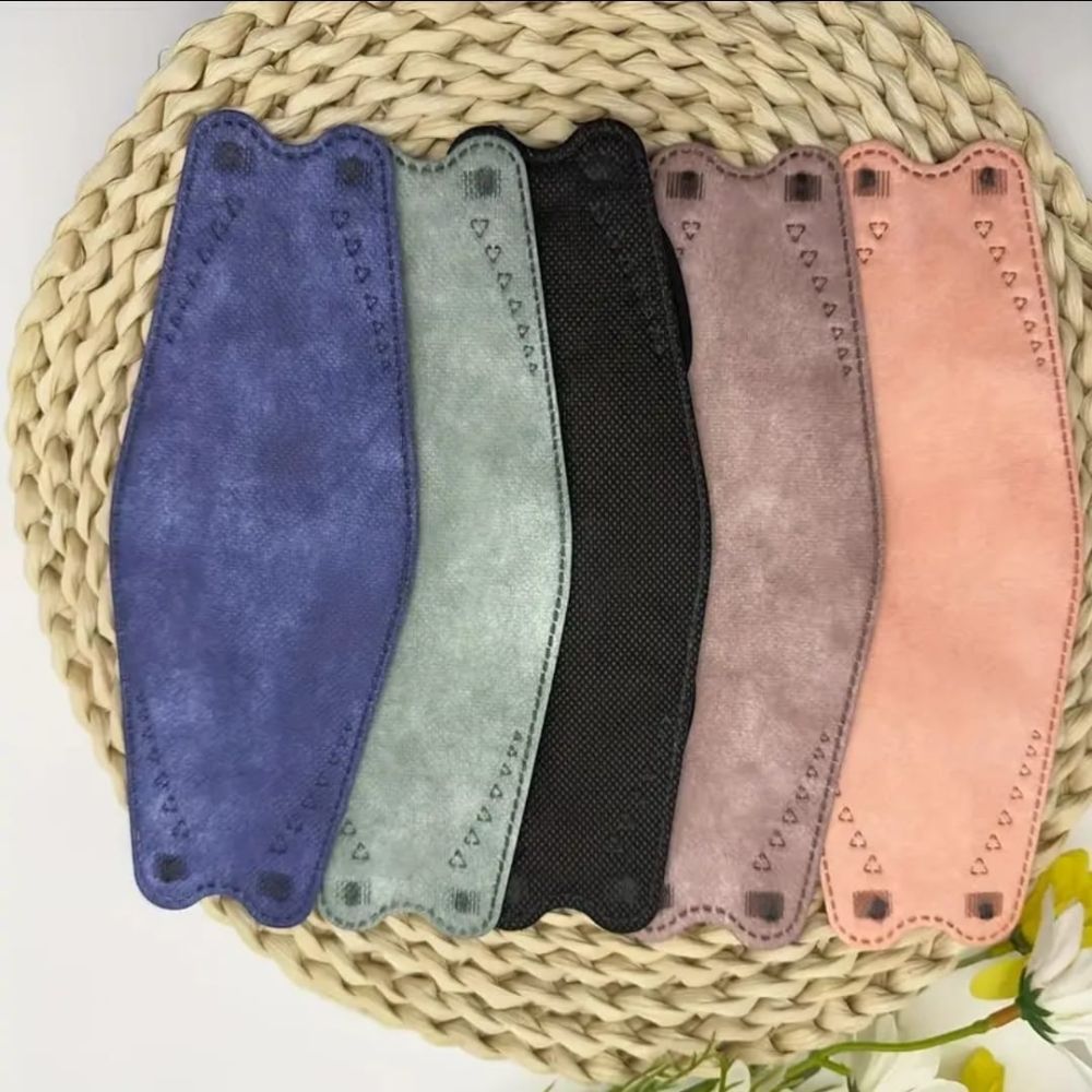 Sechs Gesichtsmasken in verschiedenen Farben. Auf einem geflochtenen Untersetzer.