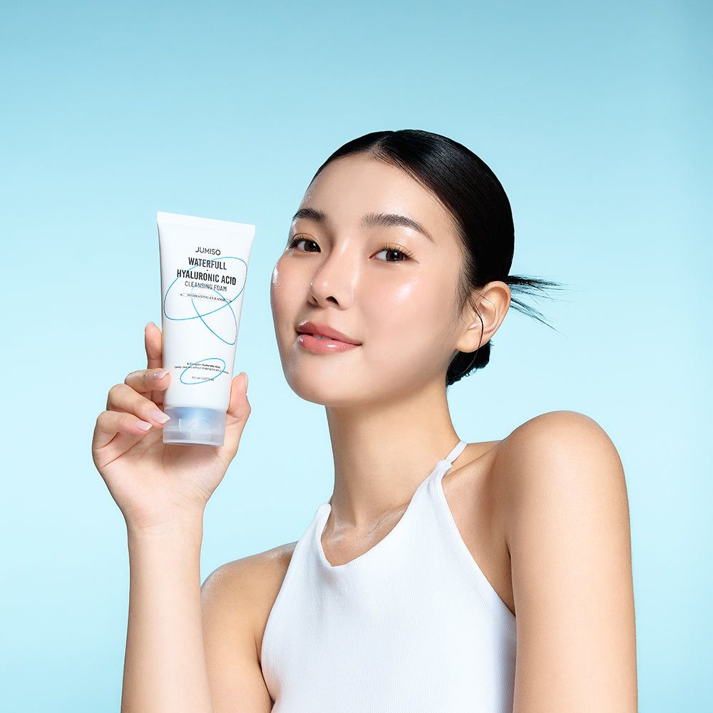 Eine Frau hält eine Tube Reinigungsschaum. Auf der Tube steht: JUMISO Waterfull Hyaluronic Acid Cleansing Foam.