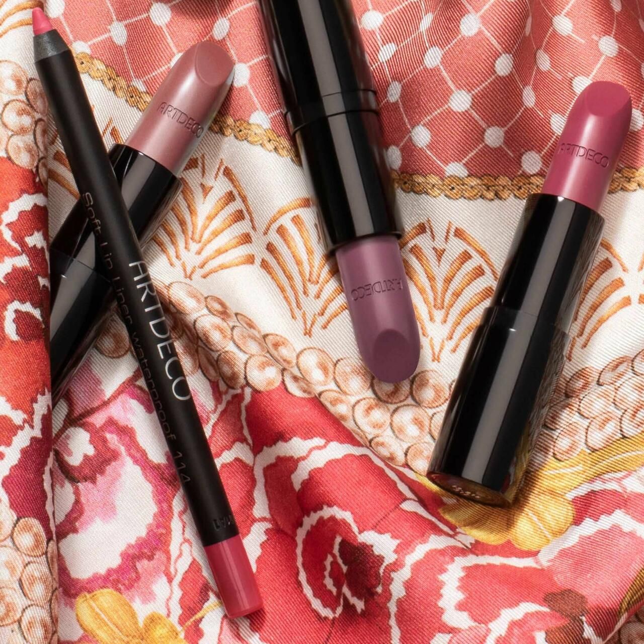 Mehrere Lippenstifte und ein Lipliner auf einem Stoff. Sichtbar: ARTDECO-Schriftzug auf dem Lipliner.