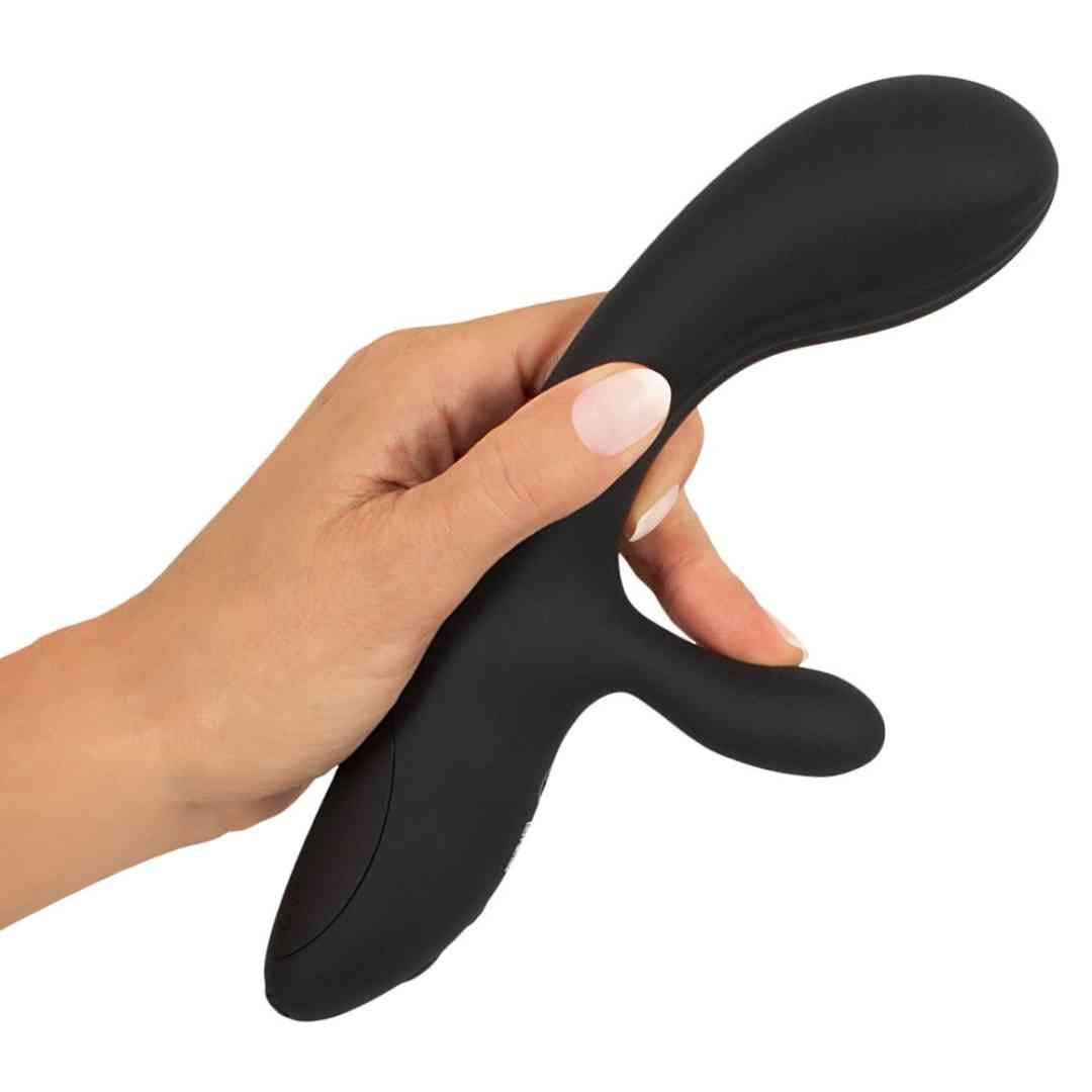 Schwarzer Vibrator in einer Hand gehalten. Gebogene Form mit einem zusätzlichen Teil.