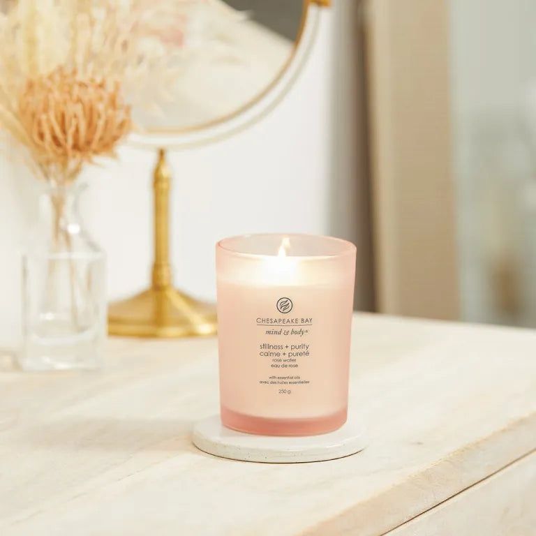 Brennende Kerze Chesapeake Bay, mind & body, stillness + purity, 250g. Auf weißem Untersetzer, Spiegel im Hintergrund.