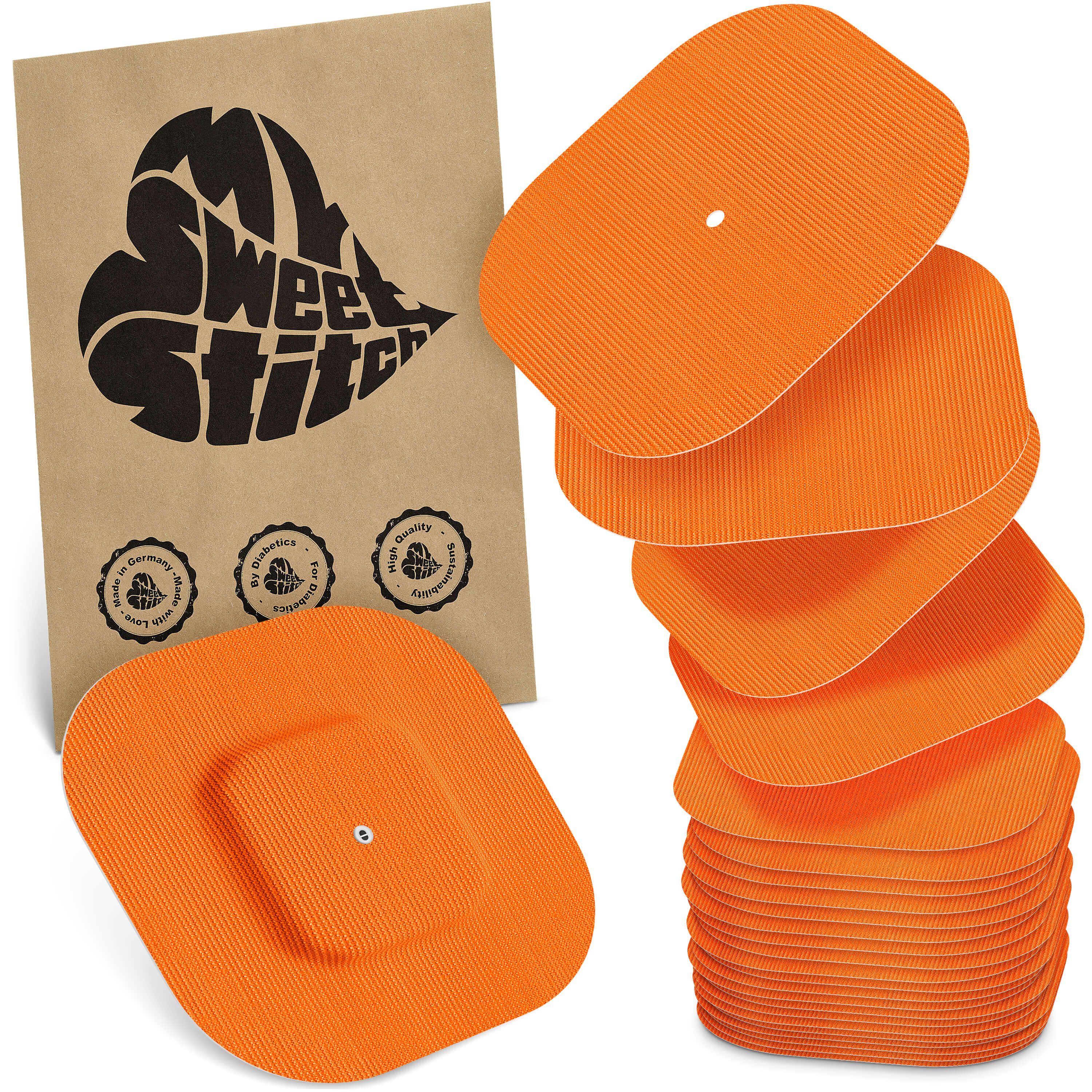 Orangefarbene Elektrodenpads mit gerippter Oberfläche und zentralem Anschlussloch. Ein Päckchen ist sichtbar.