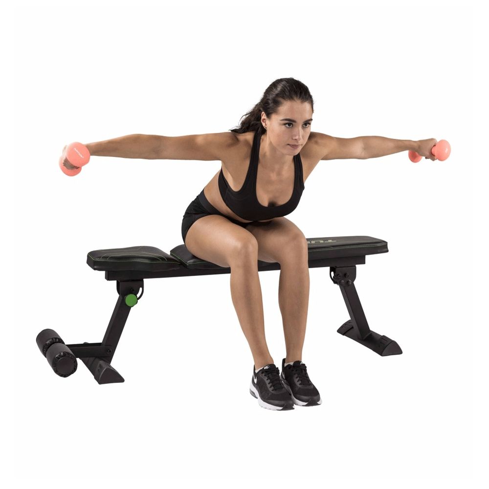 Flachbank mit Frau, die seitliches Schulterheben macht. Schwarze Bank mit grünen Akzenten. Frau sitzt auf der Bank.