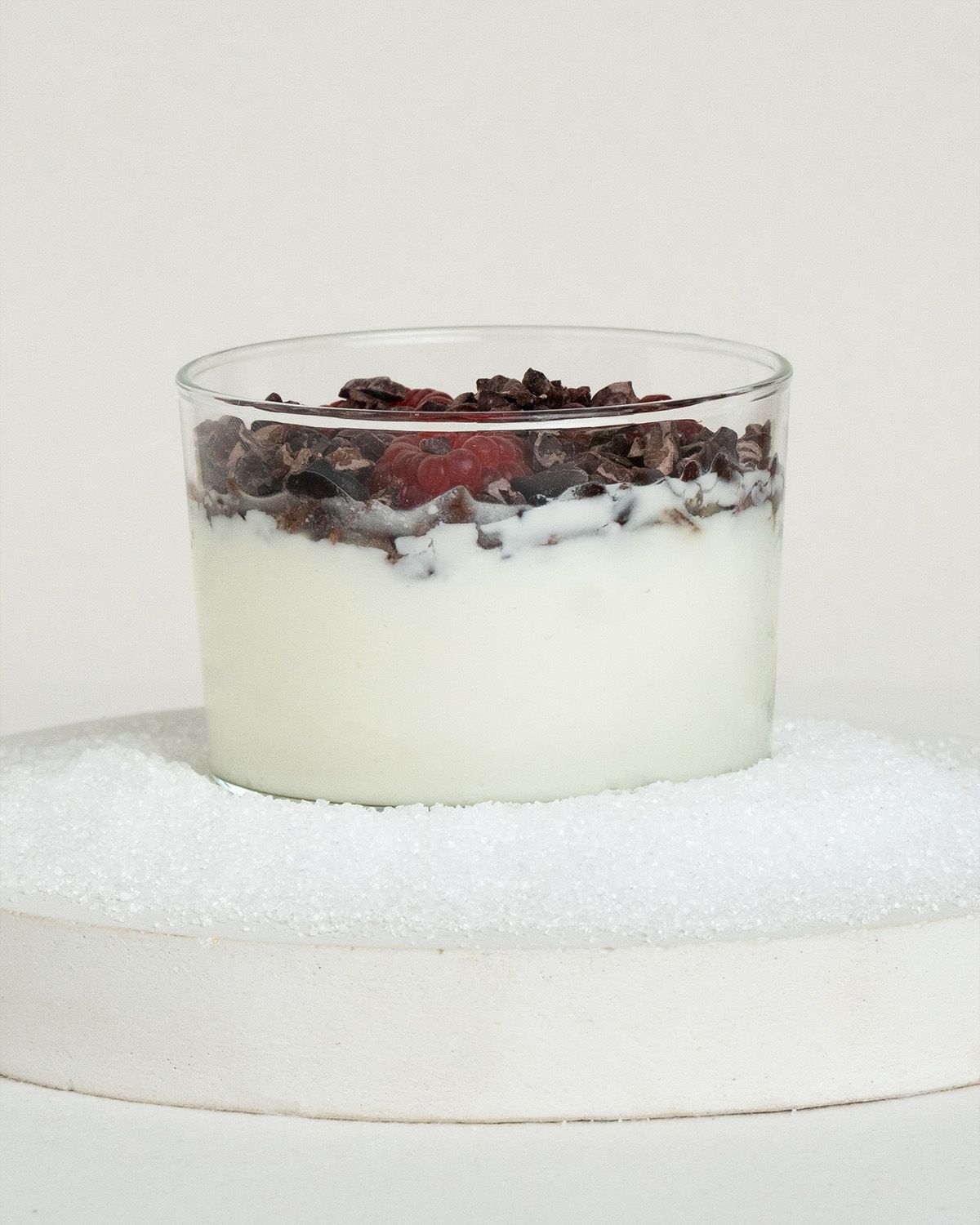 Ein Glas mit Joghurt, Beeren und Schokoladenstückchen.