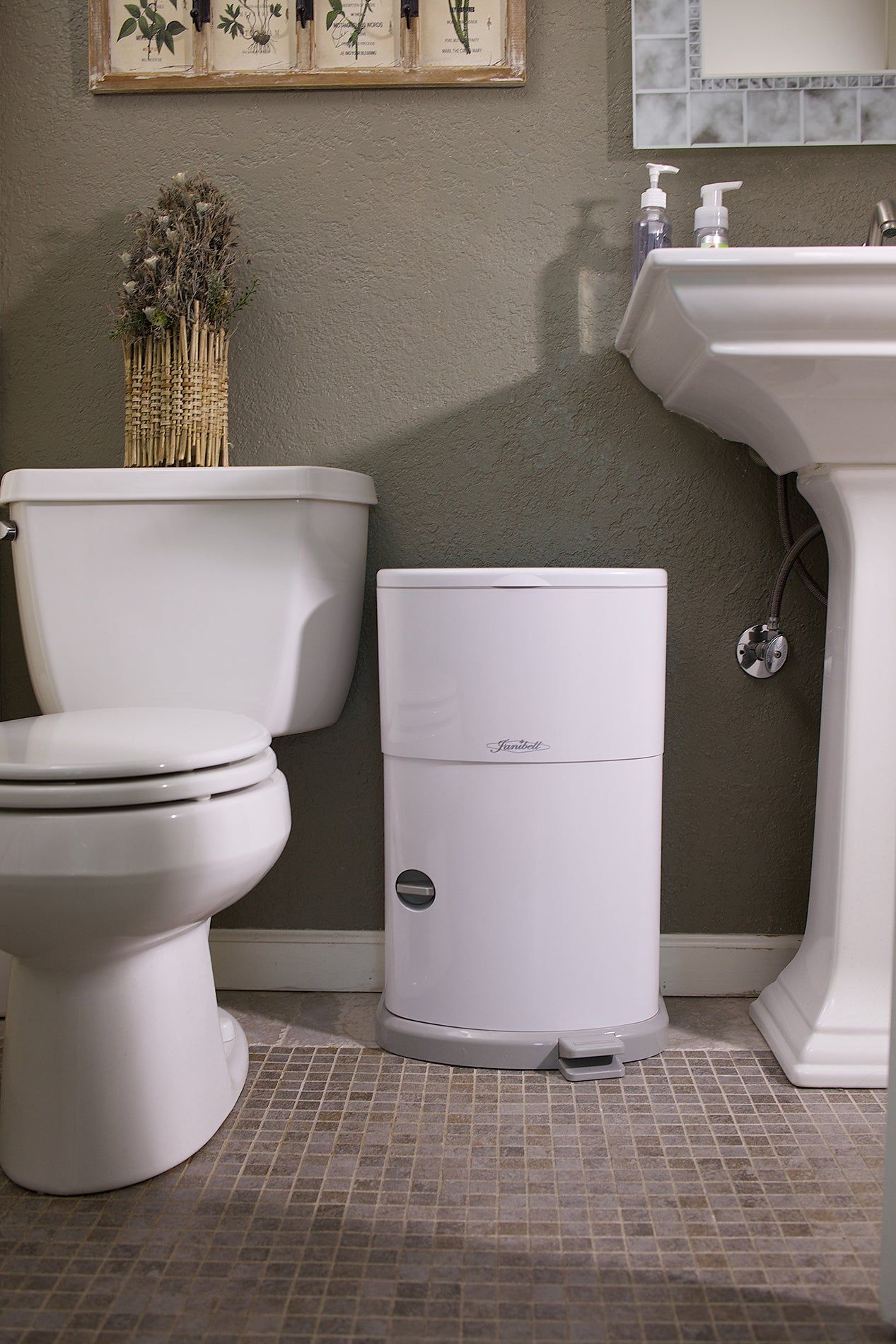 Weißer Windeleimer im Badezimmer. Grauer Fuß und Deckel. Fußpedal. Janibell-Logo.