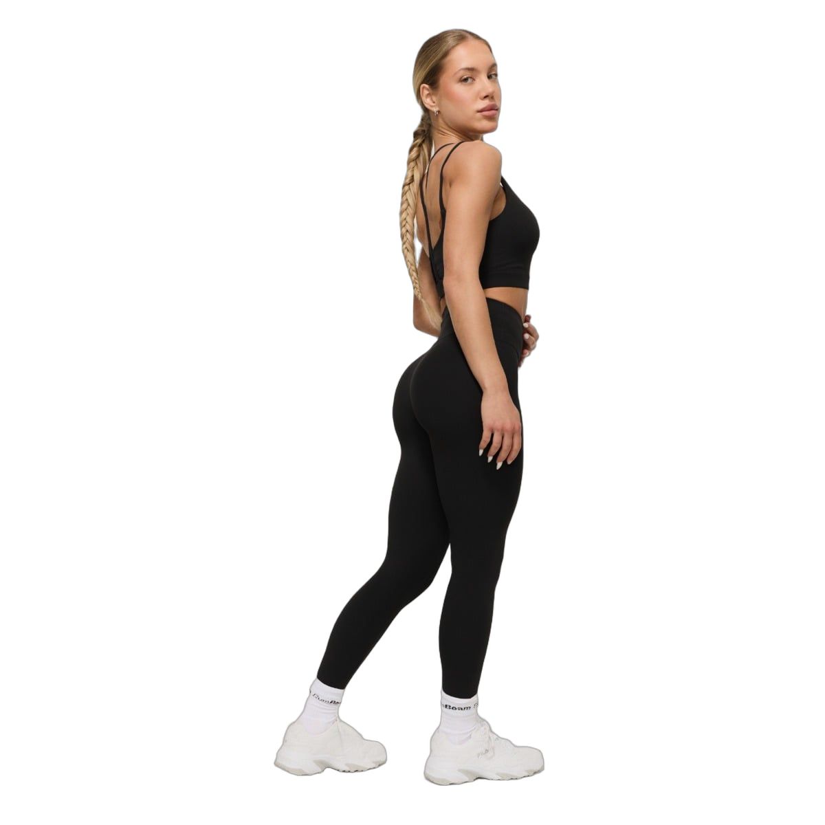 Frau in schwarzen Leggings mit hohem Bund und passendem Sport-BH, Seitenansicht.