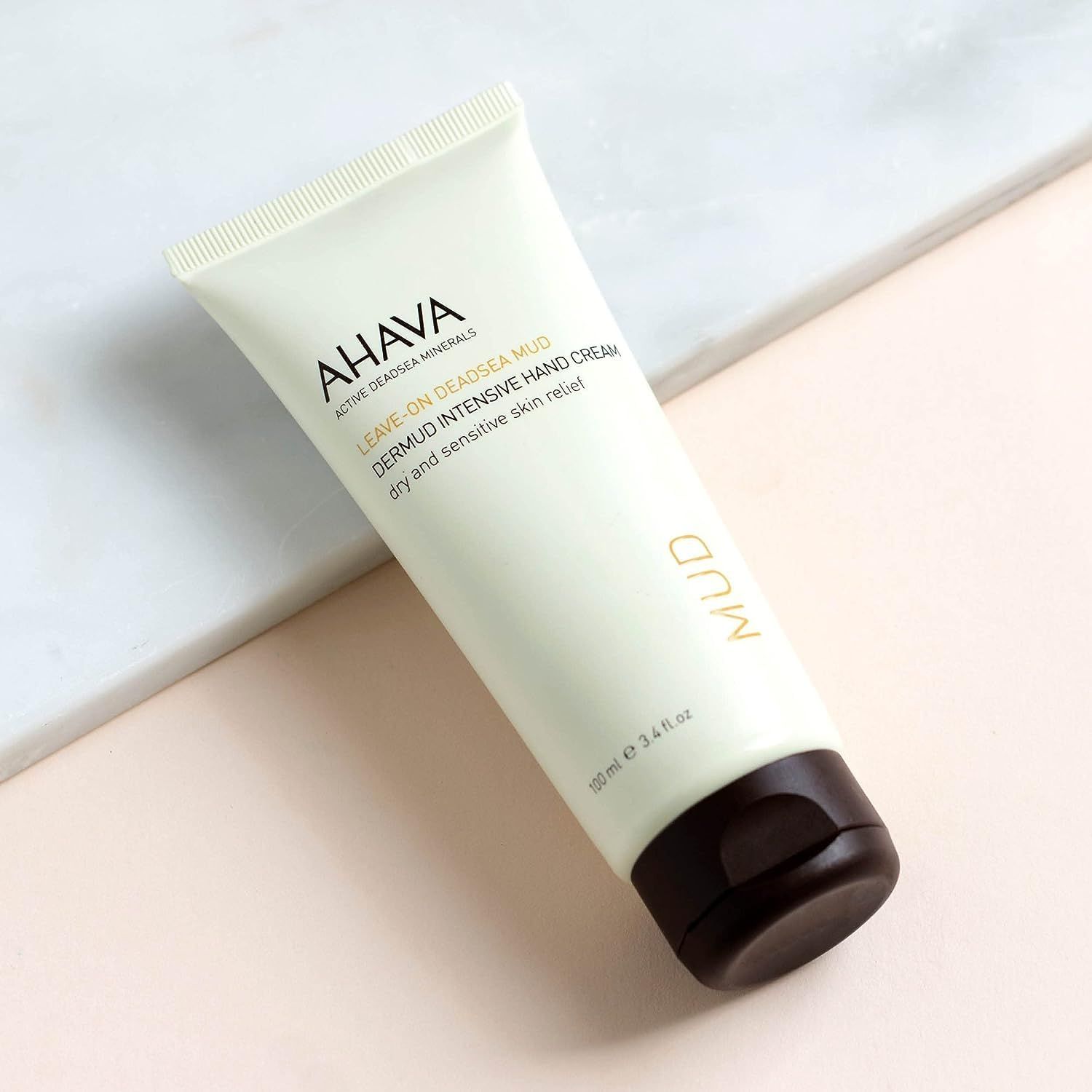 AHAVA Dermud Intensive Hand Cream Tube. Auf weißem Hintergrund, leicht schräg. Brauner Verschluss.