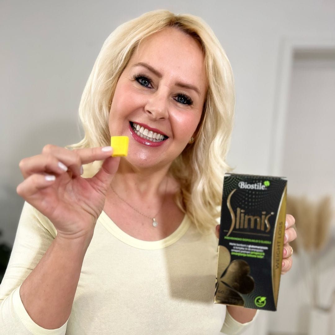 Frau hält eine gelbe Süßigkeit und eine "Biostile Slimis" Packung. Lächelt in die Kamera. Hintergrund unscharf.
