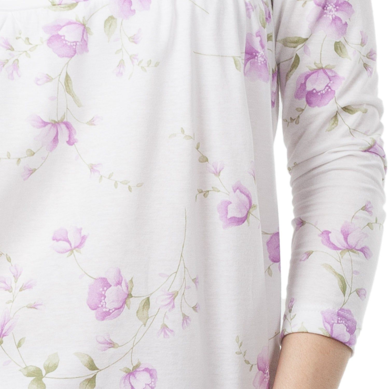 Nahaufnahme des floralen Musters auf einem weißen Stoff. Lila Blüten und grüne Blätter.