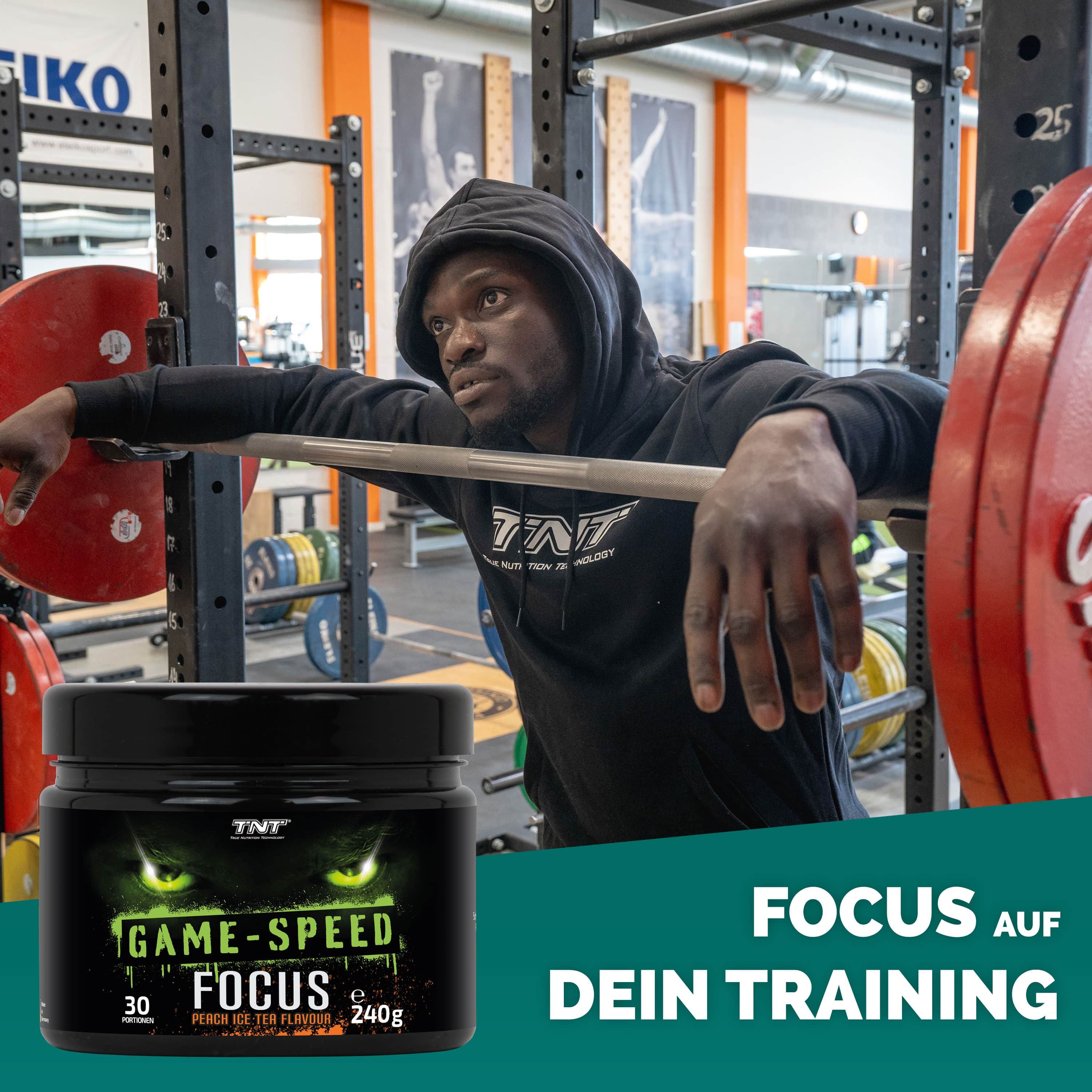 Mann im Fitnessstudio mit TNT Game Speed Focus Dose. Aufschrift: GAME-SPEED FOCUS, 30 Portionen, 240g, Peach Ice Tea Flavour. TNT Logo.