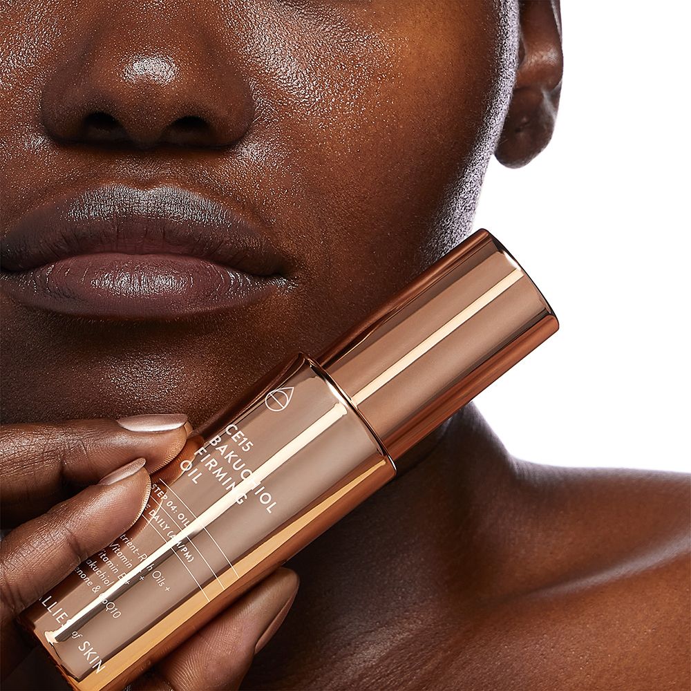 Ölflasche, kupferfarben, mit Produktnamen und Marke. Teilweise sichtbar: Gesicht einer Person.