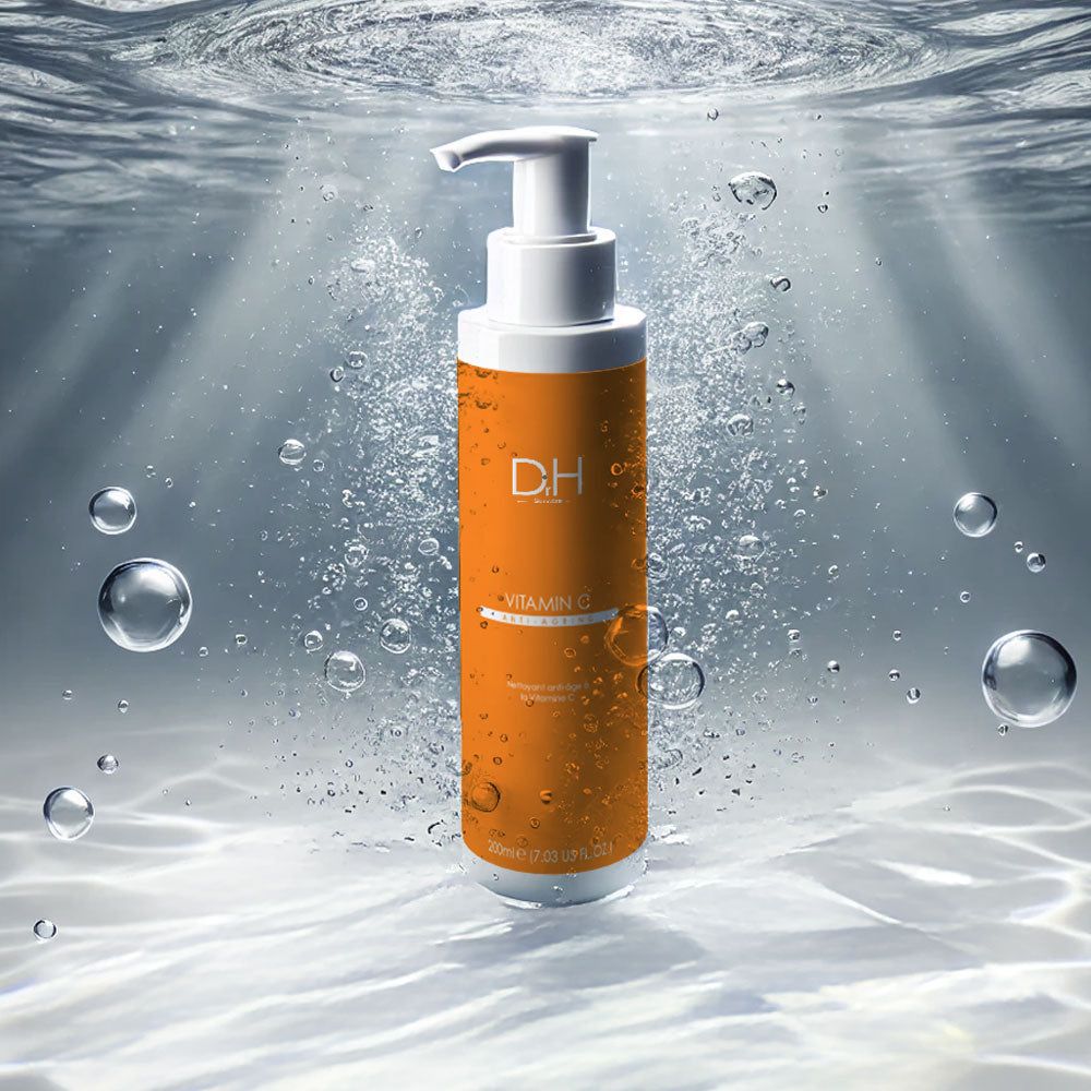 Orangefarbene Flasche mit Pumpe unter Wasser. Aufschrift: D.H. Vitamin C Anti-Aging. Weiße Schrift auf orangefarbenem Hintergrund.