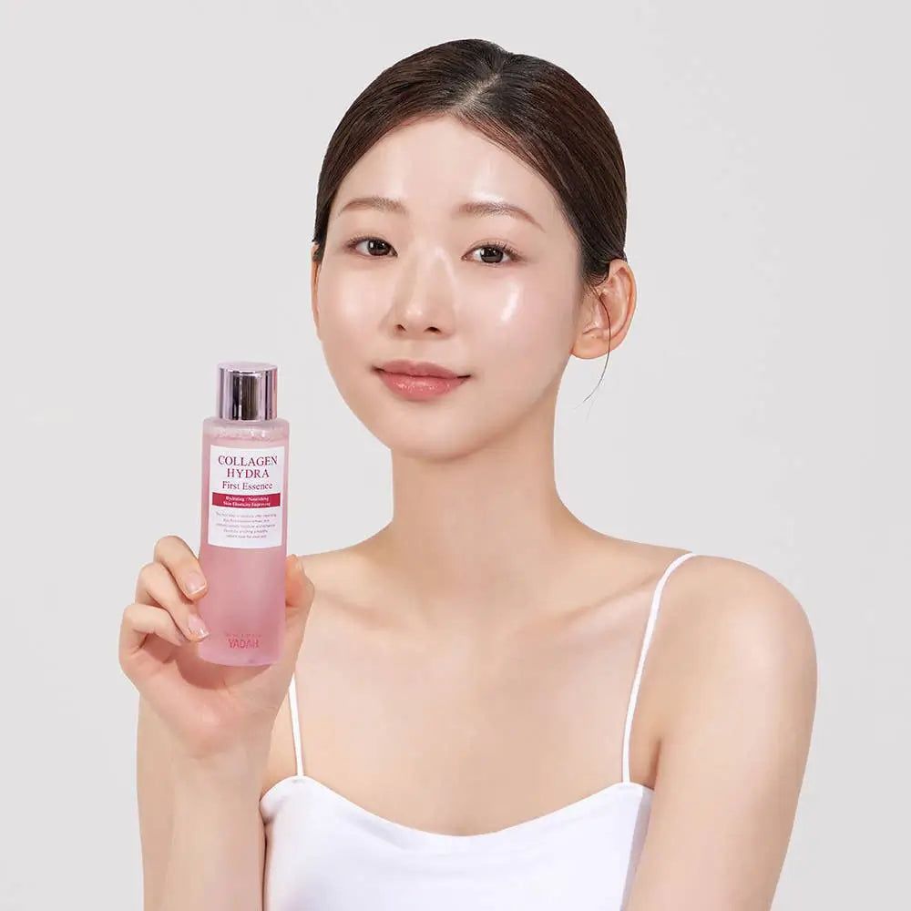 Frau hält eine Flasche mit rosa Flüssigkeit. Aufschrift: Collagen Hydra First Essence. Frau trägt ein weißes Top.