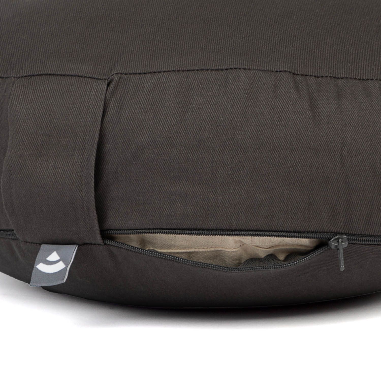 Rundes, braunes Meditationskissen mit Reißverschluss und Trageschlaufe. Logo-Etikett an der Seite.