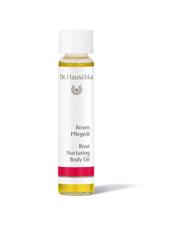 Körperölflasche mit weißem Etikett. Aufschrift: Dr. Hauschka, Rosen Pflegeöl, Rose Nurturing Body Oil. Roter Streifen am unteren Ende.