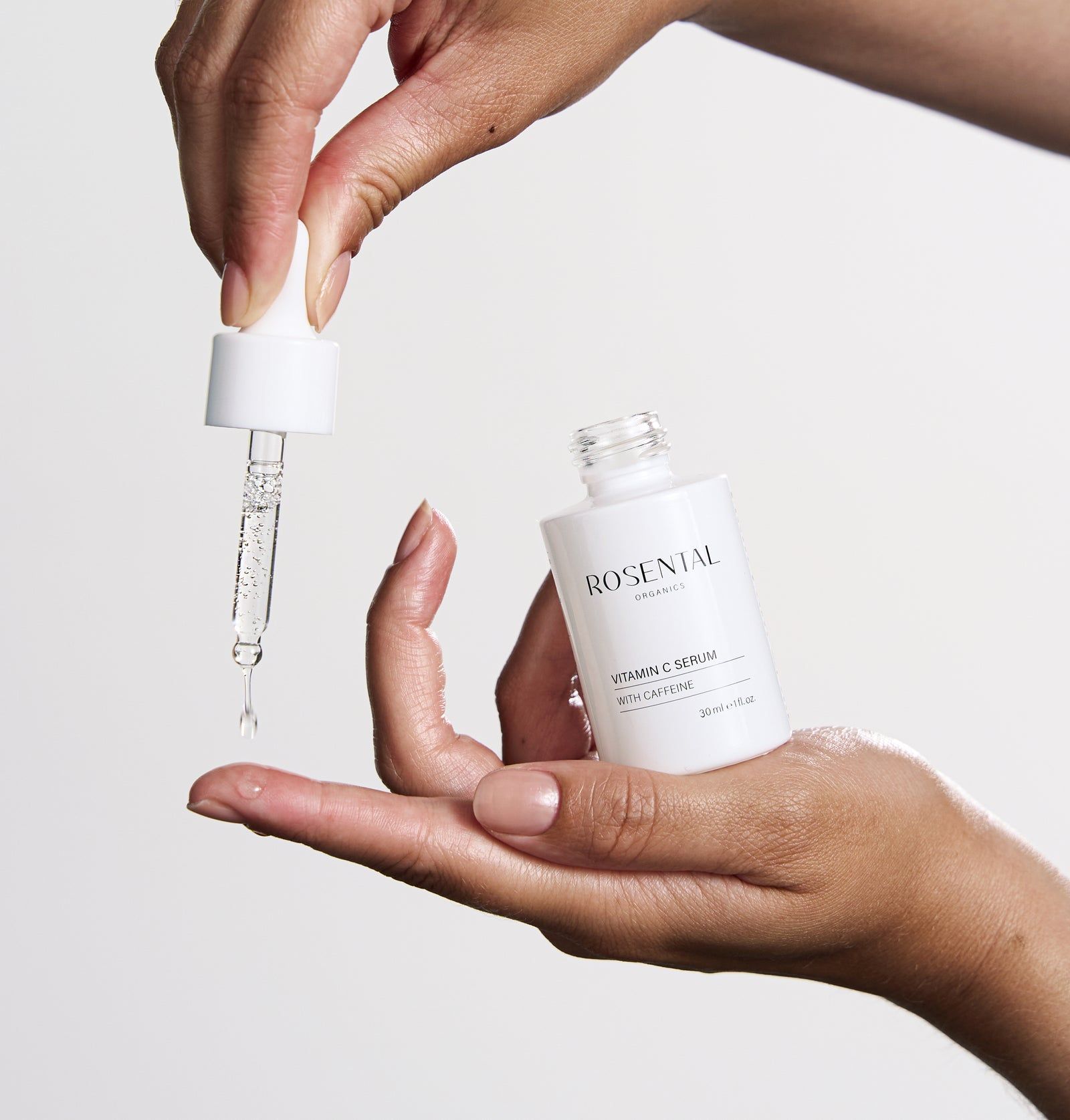 Hände halten eine Serumflasche und eine Pipette. Tropfen fallen aus der Pipette.