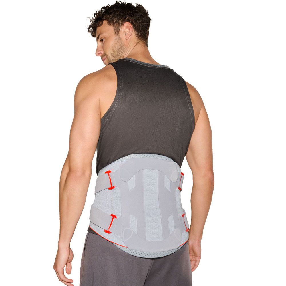 Mann trägt eine graue Rückenbandage mit roten und grauen Klettverschlüssen und Verstärkungen.