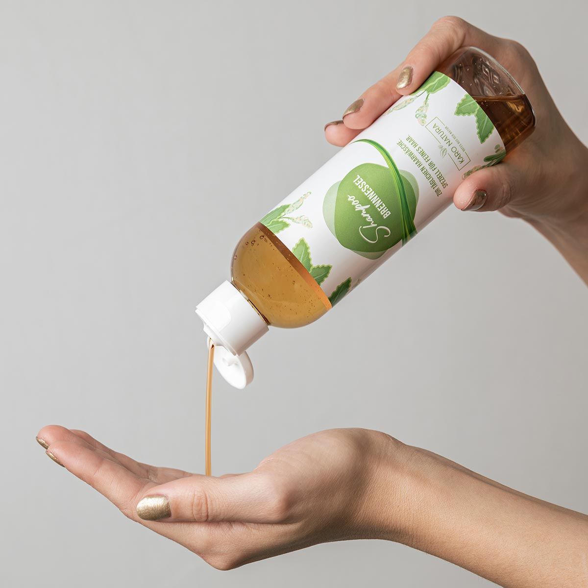 Hände halten Shampoo-Flasche. Shampoo wird in die Hand gegossen. Flasche mit grünem Etikett.