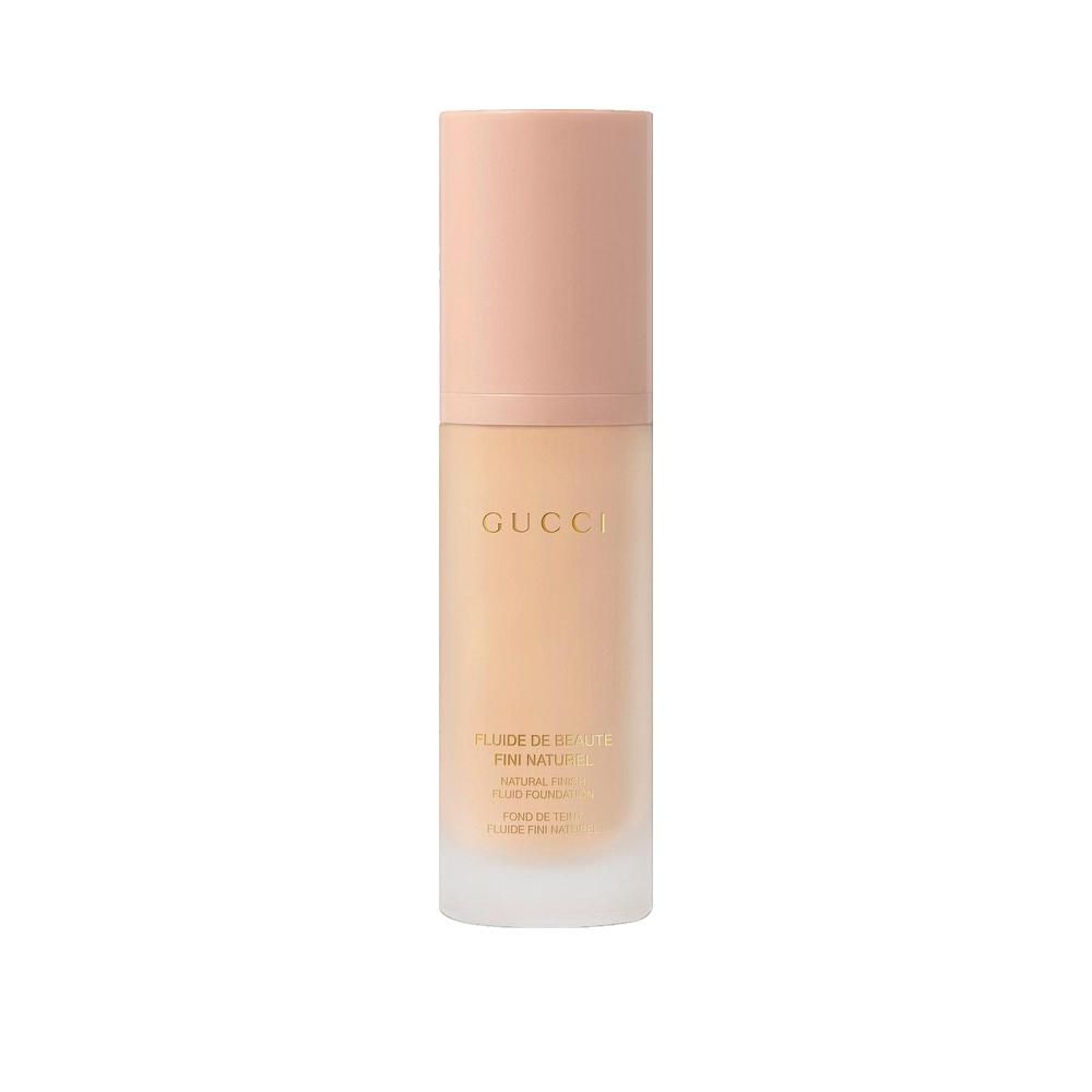 Gucci Fluide de Beauté Natürlicher Abschluss. Flasche mit rosafarbenem Deckel. Aufschrift Gucci. Beige Flüssigkeit sichtbar.