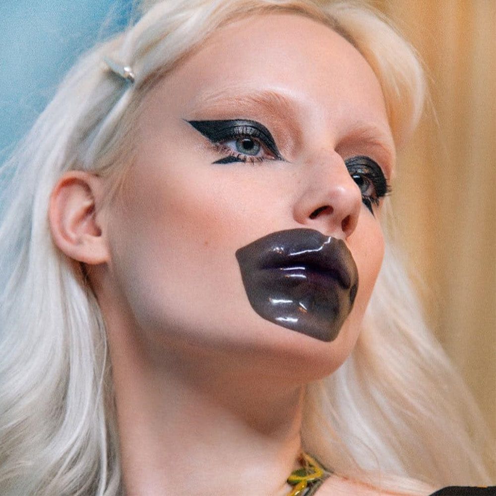 Person mit schwarzer Lippenmaske. Maske bedeckt die Lippen. Haut ist hell. Haare sind blond.
