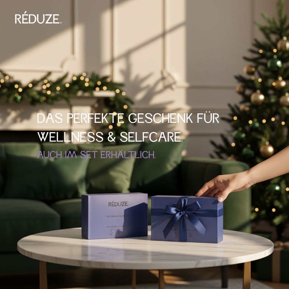 Zwei Geschenkboxen mit blauer Schleife. RÉDUZE ist sichtbar. Auf einem Tisch mit Weihnachtsdeko.