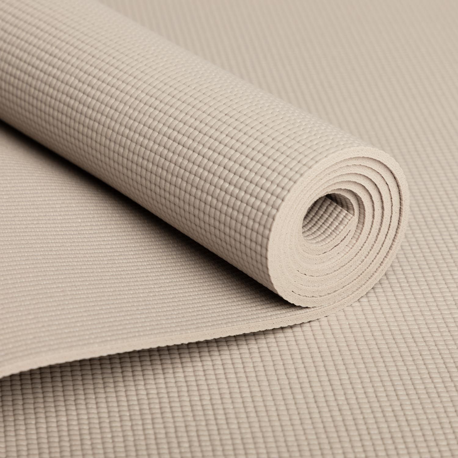 Nahaufnahme einer gerollten, beigen Yogamatte. Geriffelte Oberfläche. Bodhi-Logo.