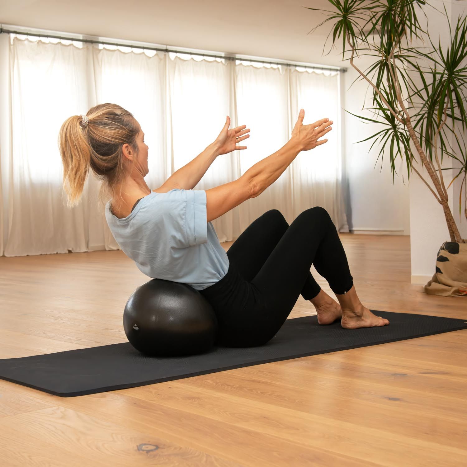 Frau macht Pilates auf einem Ball sitzend.