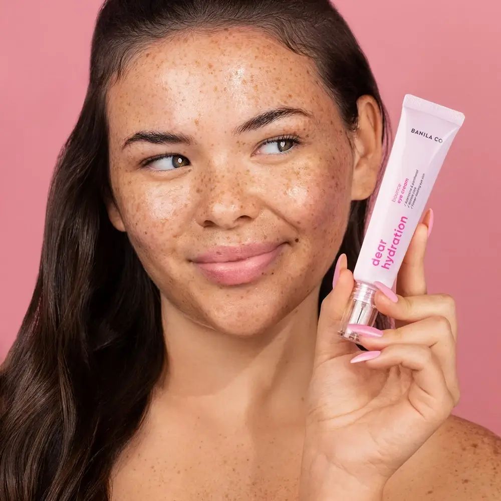 Frau hält eine rosa Tube Augencreme. Auf der Tube steht "BANILA CO Dear Hydration".