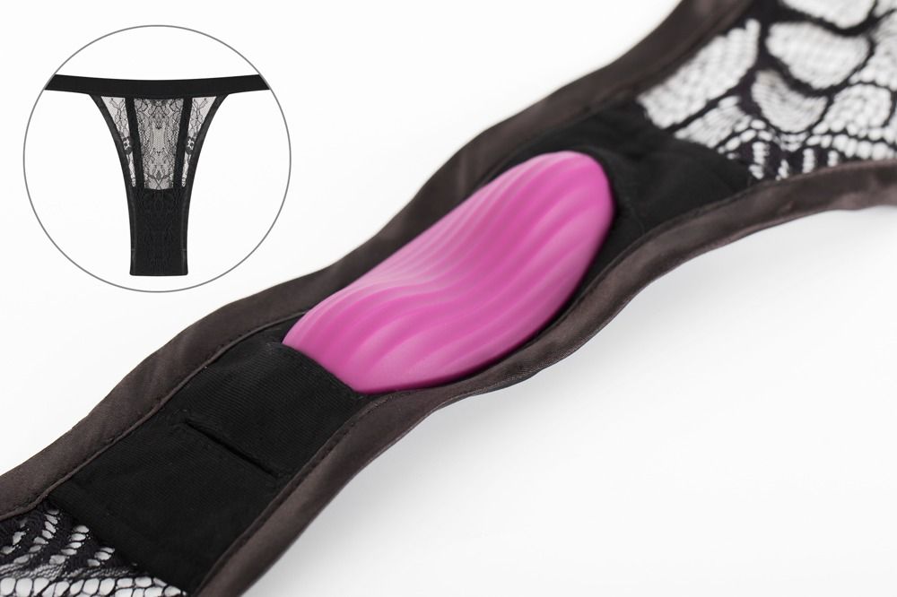 Schwarzer String-Tanga mit Spitze und einem violetten Vibrator. Der Vibrator ist in einer Tasche.