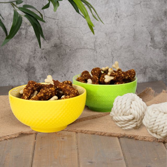 Zwei Schalen mit Hühnchenschenkel-Snacks. Gelbe und grüne Schalen. Dekorative Kordelknoten.