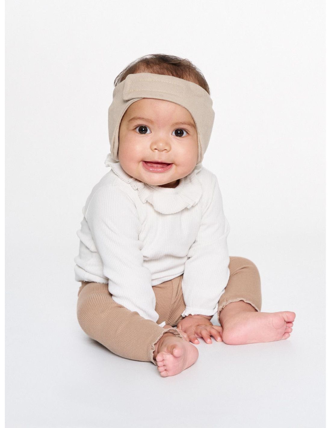 Baby mit beigem Kopfband, das mit einem Muster verziert ist.