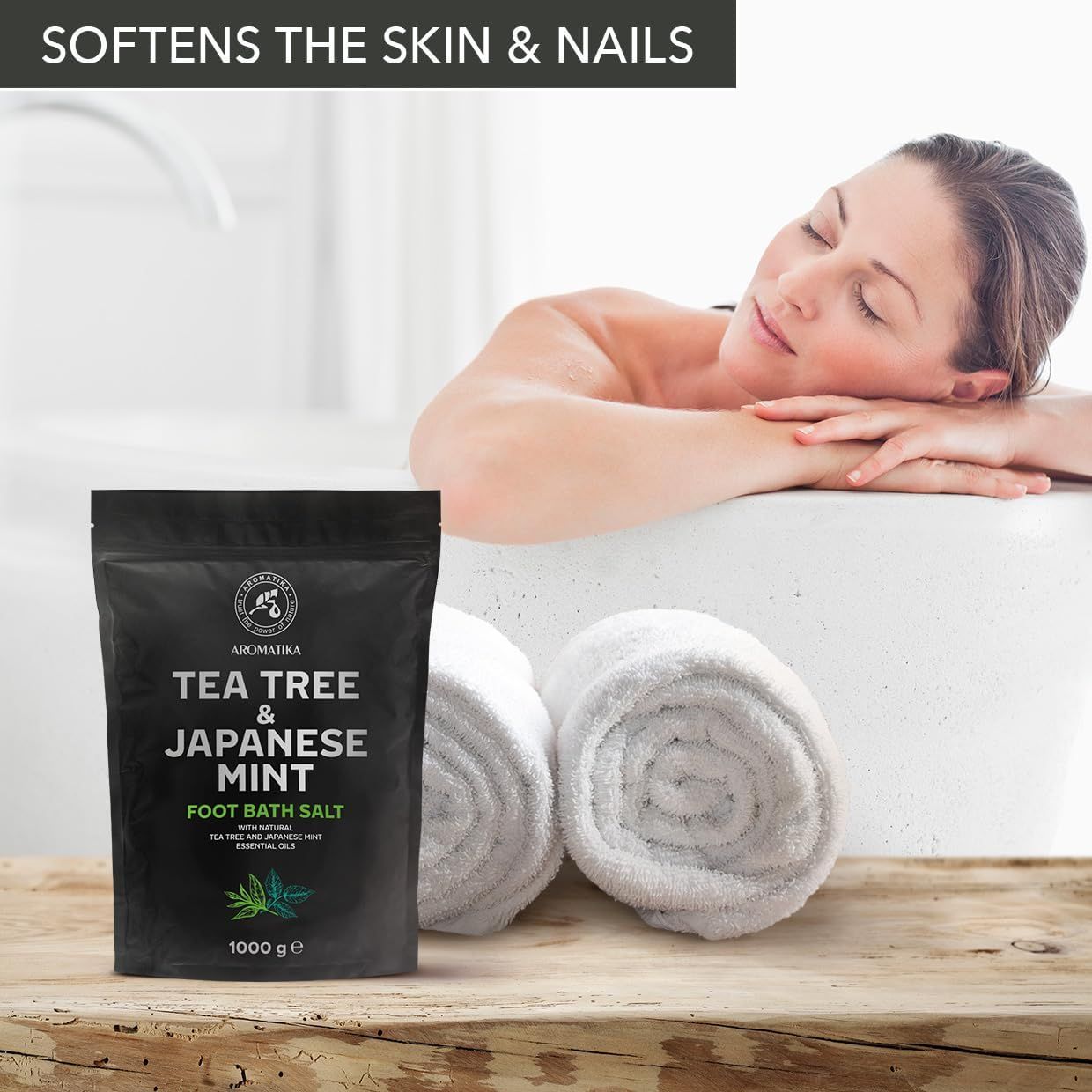 Frau in Badewanne mit Handtüchern. Schwarze Verpackung mit Produktnamen und Logo. Text: Tea Tree & Japanese Mint Foot Bath Salt.