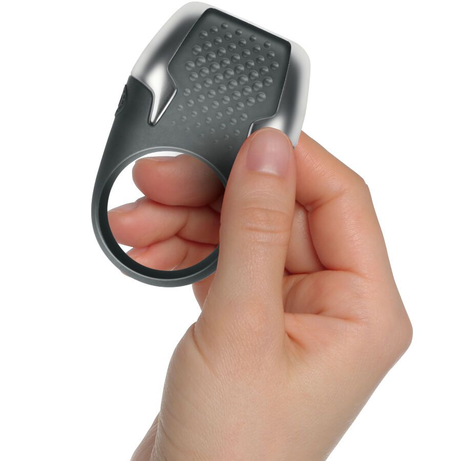 Grauer Penisring mit Noppen und LED-Lichtern, gehalten von einer Hand. Ringförmige Öffnung. Oberteil mit silbernen Akzenten.