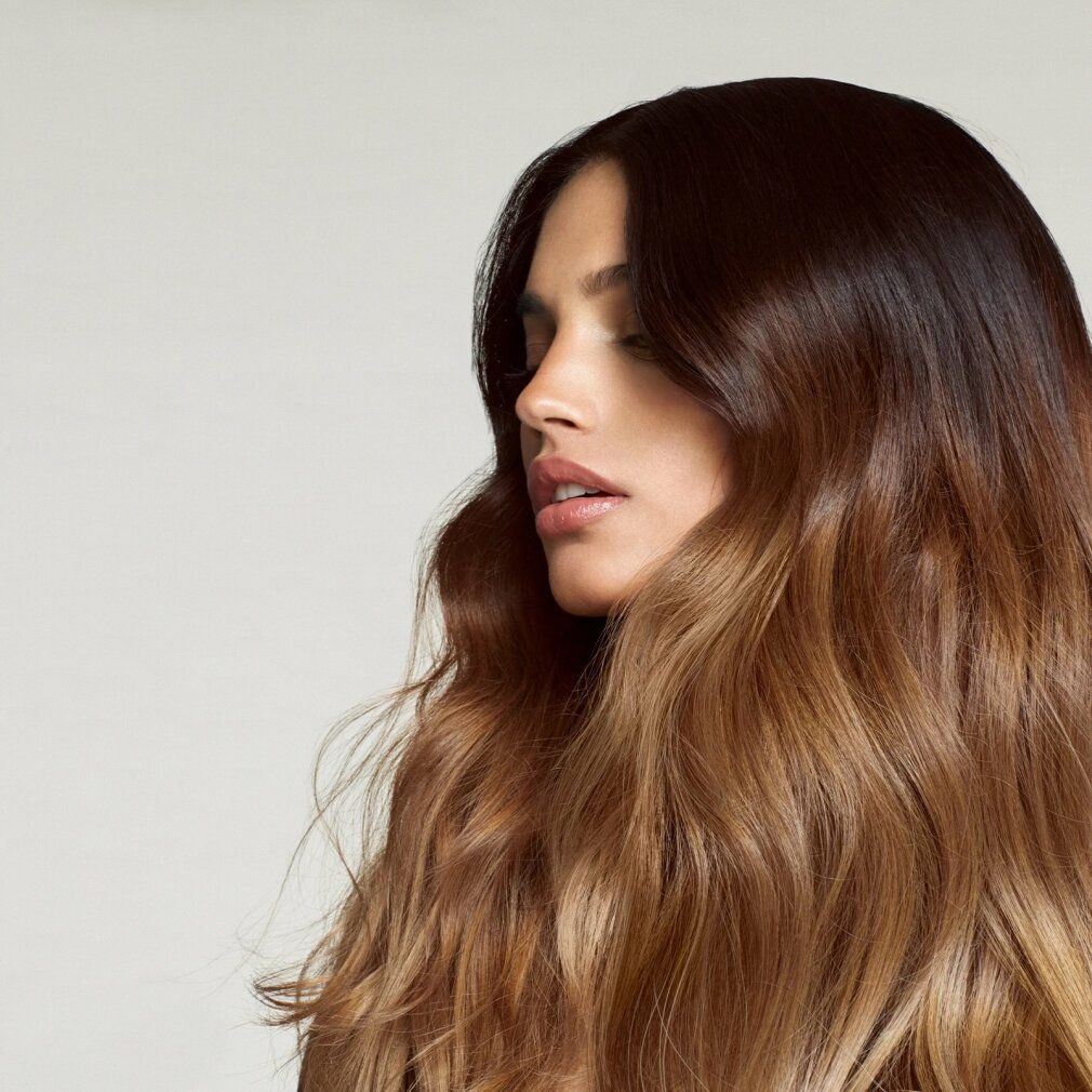 Porträt einer Frau mit braunem Haar. Haare mit Ombre-Effekt, von dunkelbraun zu hellbraun. Gesicht im Profil.