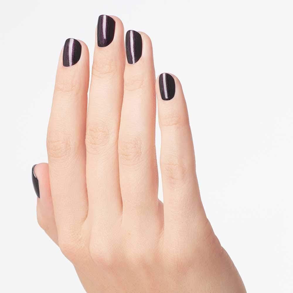 Hand mit lackierten Nägeln. Dunkelvioletter Nagellack auf fünf Fingern.