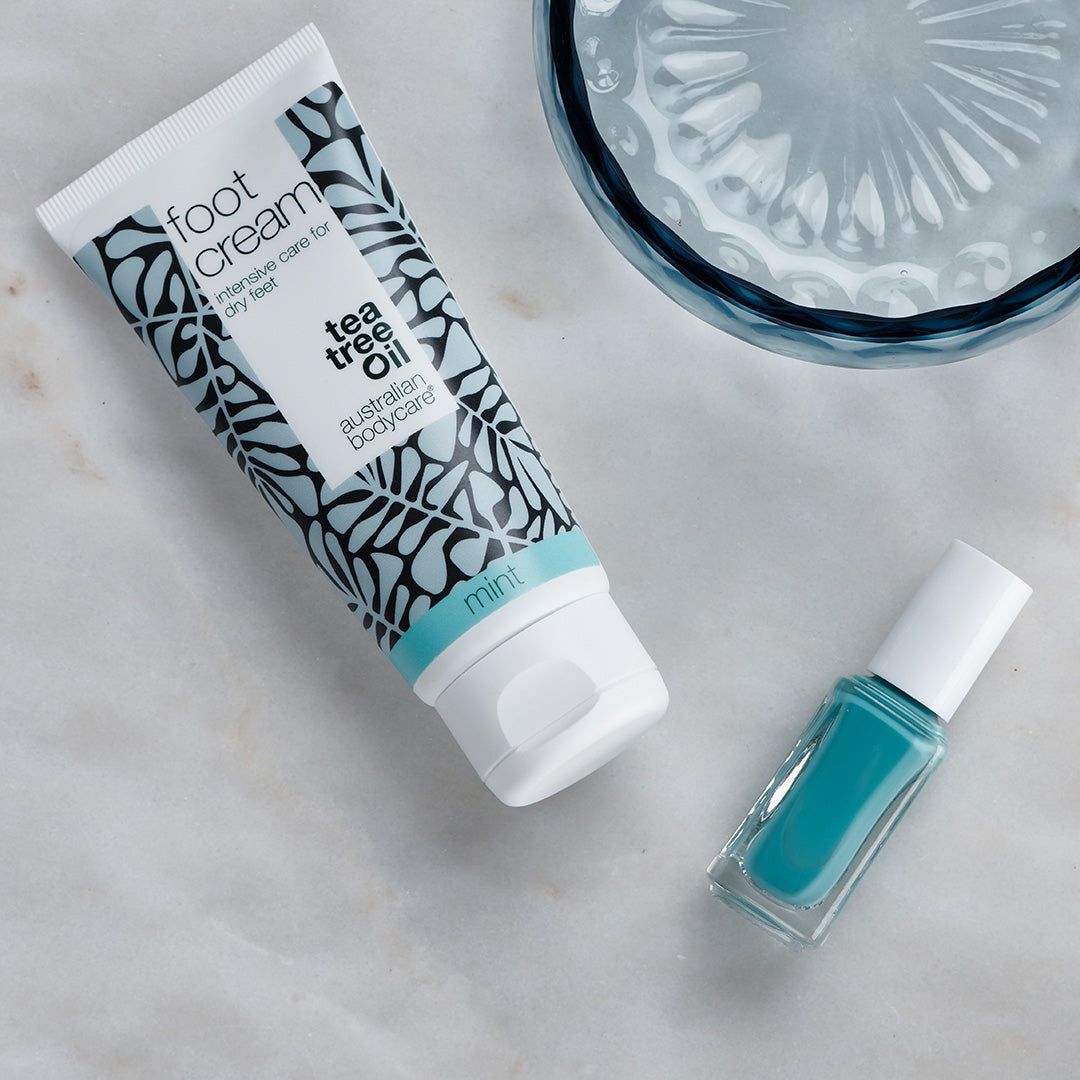 Fußcreme-Tube und Nagellack. Aufschrift: "foot cream", "tea tree oil", "mint", "australian bodycare". Nagellackflasche.