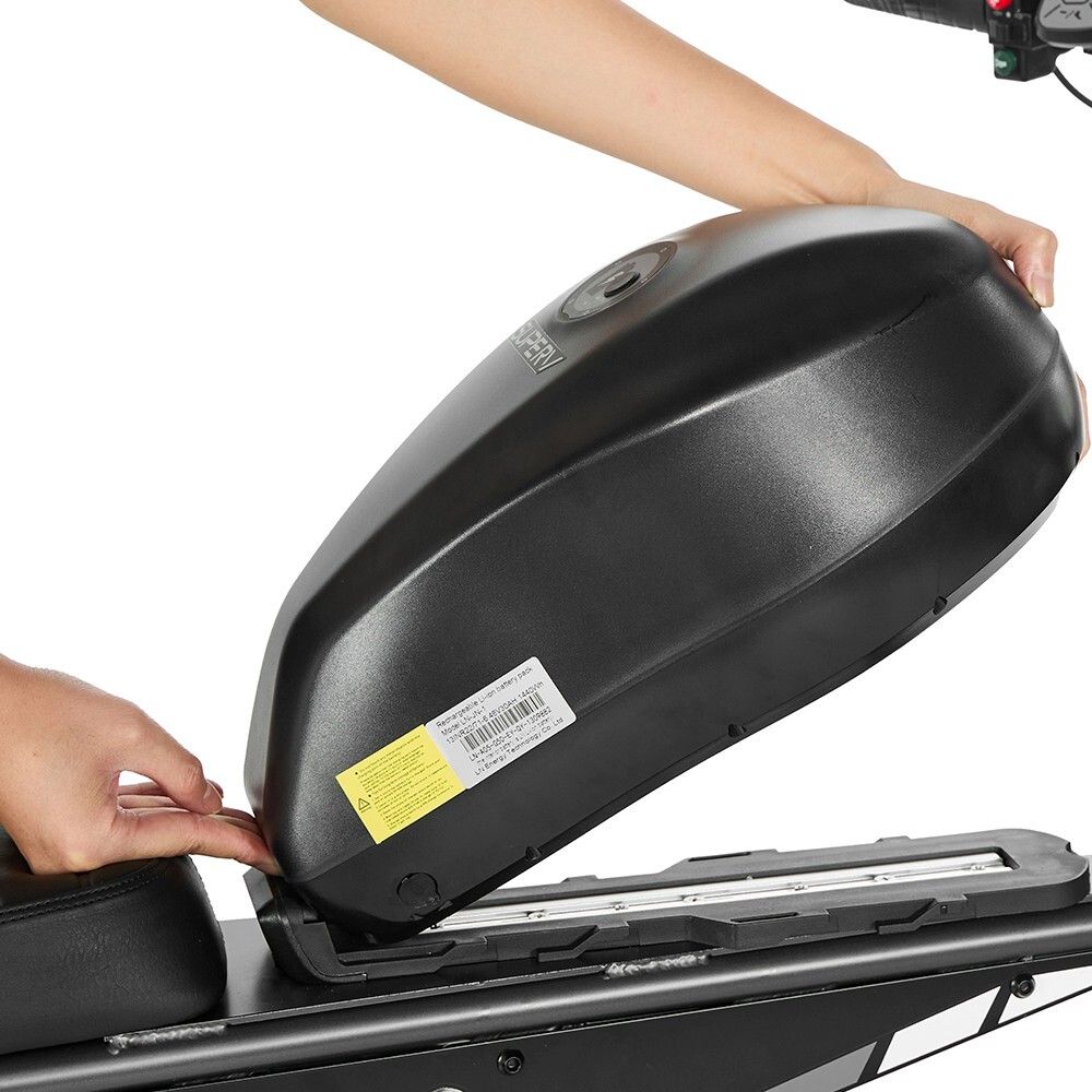 Person legt schwarzen Akku auf das Dirtbike. Schwarzer Rahmen, Akku mit Aufklebern. Hände im Bild.