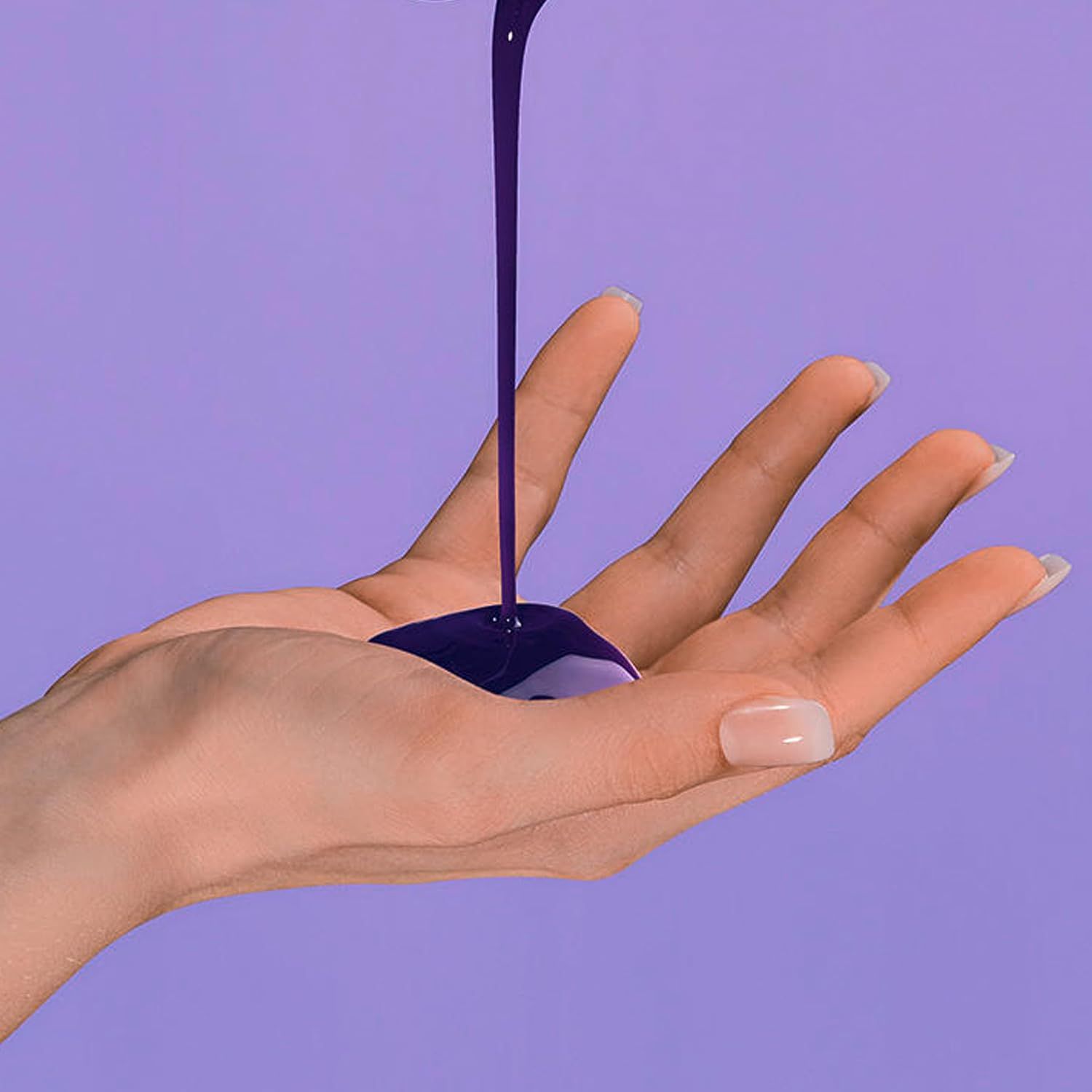 Lila Flüssigkeit wird in eine offene Handfläche gegossen.