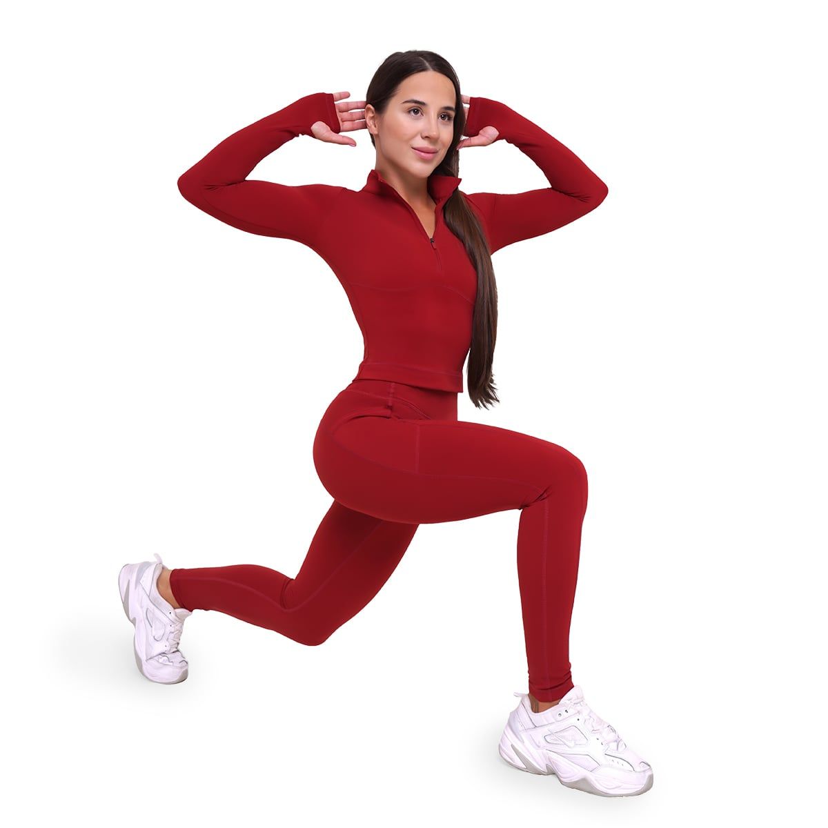 Frau in dunkelrotem Sport-Set: Leggings mit hoher Taille und Langarmshirt, macht Ausfallschritt.