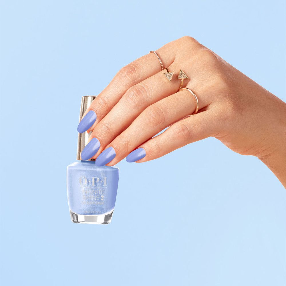 Hand hält Nagellackflasche und hat hellblau lackierte Fingernägel. Blauer Hintergrund.