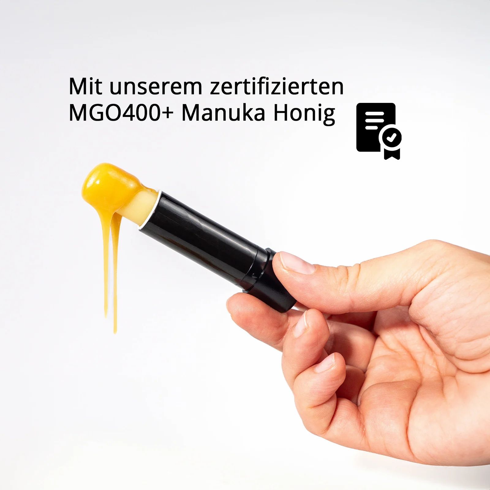Hand hält Lippenpflegestift mit Manuka Honig. Text: Mit unserem zertifizierten MGO400+ Manuka Honig.