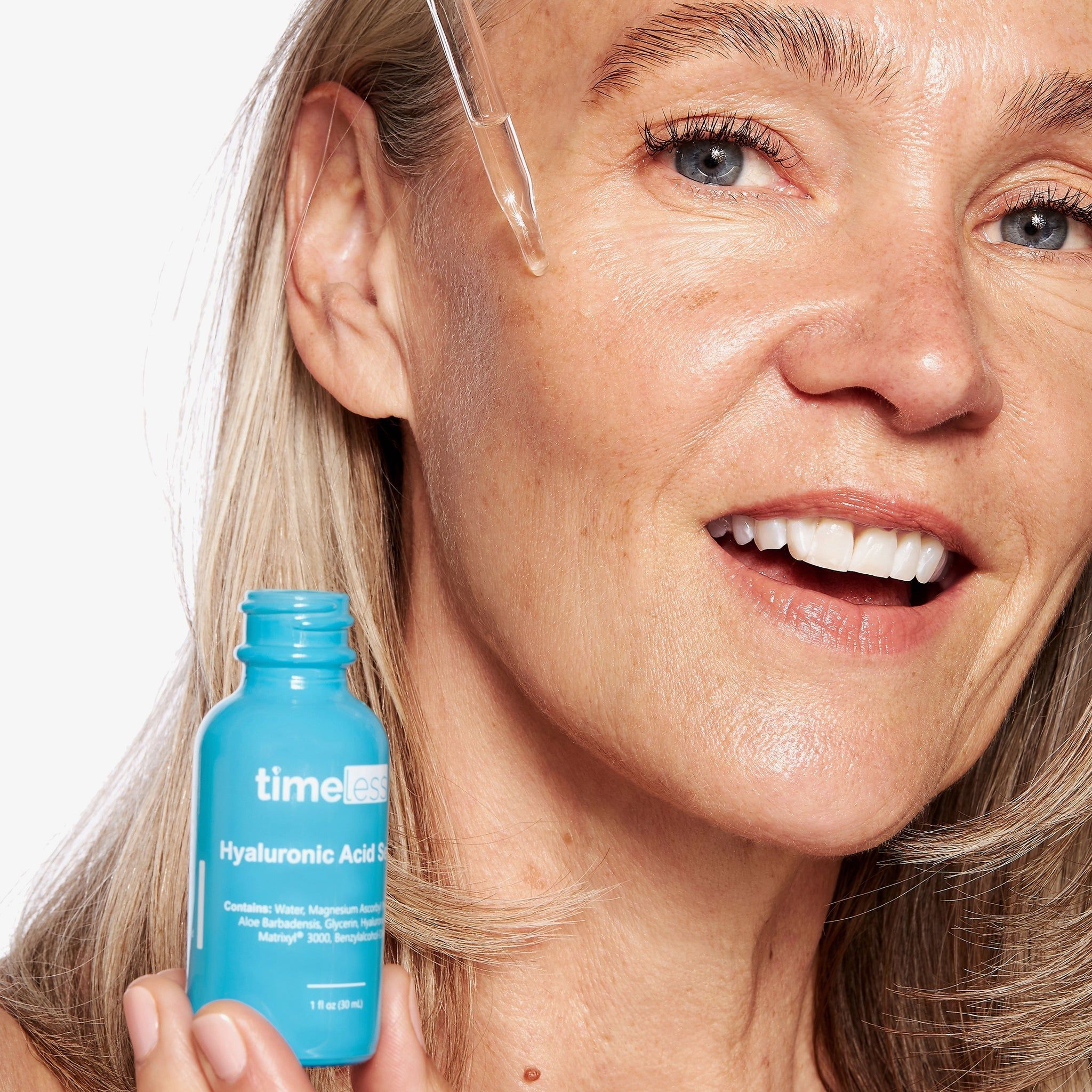 Frau mit Serum-Applikator. Blaue Flasche mit Aufschrift: timeless, Hyaluronsäure Serum. Frau mit Serum auf der Haut.