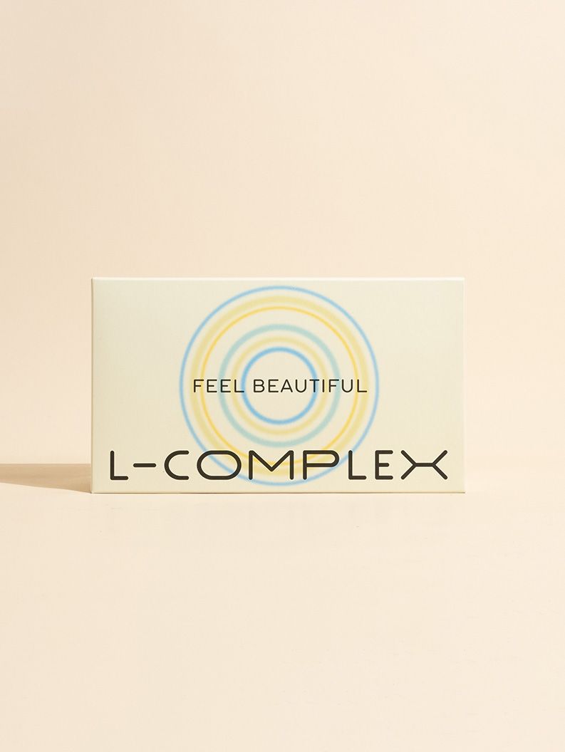 Karton mit Aufschrift FEEL BEAUTIFUL und L-COMPLEX. Gelb-blaue Kreise als Designelement.