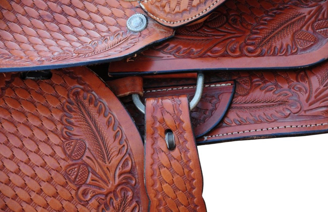 Detailansicht eines braunen Westernsattels. Metallring und Lederriemen. Florale Prägungen auf dem Leder sichtbar.