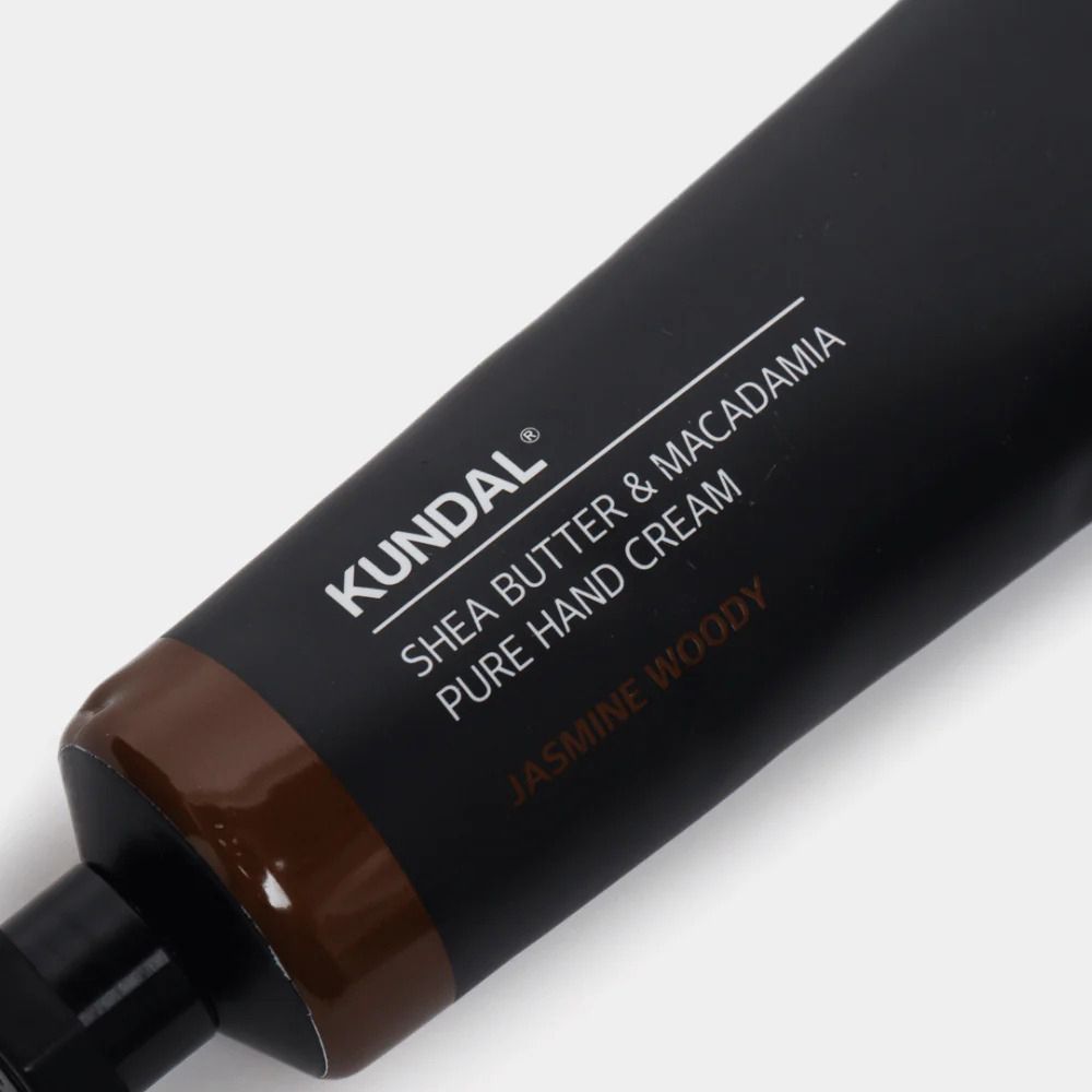 Nahaufnahme einer schwarzen Handcreme-Tube. Aufschrift: KUNDAL Shea Butter & Macadamia Pure Hand Cream Jasmine Woody.