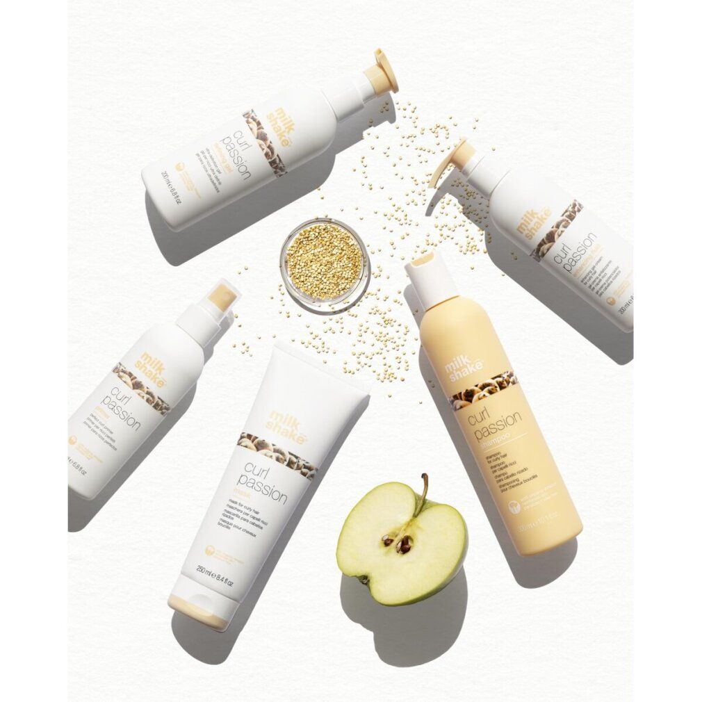 Verschiedene "milk shake curl passion" Produkte, darunter Tuben und Flaschen. Dazu Apfel und Samen.