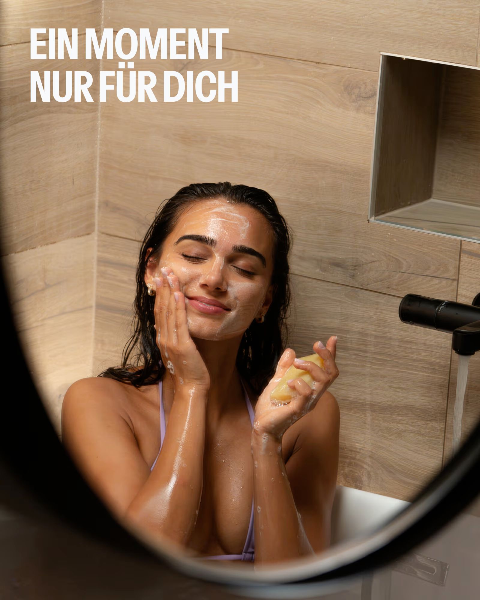 Frau wäscht sich im Bad das Gesicht mit Seife und Schaum.